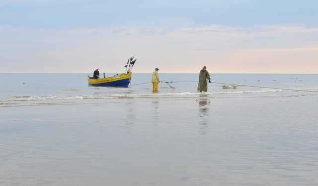 Rybacy wciągający łódź na brzeg