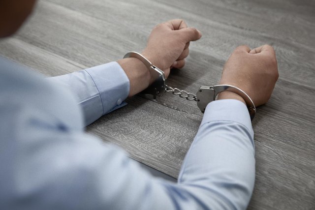 selective-focus-shot-male-hands-handcuffs-wooden-table.jpg