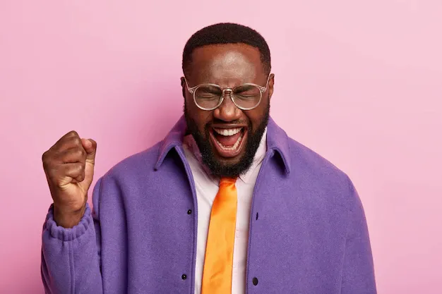 pleased-dark-skinned-man-raises-clenched-fist-shouts-yeah-celebrates-success-wears-orange-tie-purple-jacket-stands-against-pastel-space_273609-38623.webp