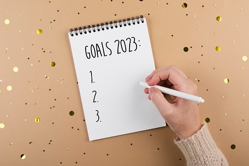 new-year-goals-2023-womans-hand-writing-in-note-pad-goals-list-concept-of-new-year-planning.jpg