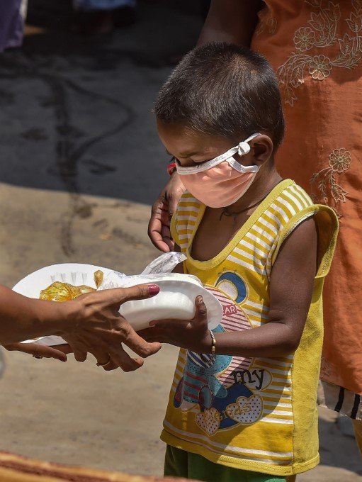 a-boy-wearing-face-mask-receives-food-from-volunteers-during-ongoing-covid-19-lockdown-in-kolkata_158839189180.jpg