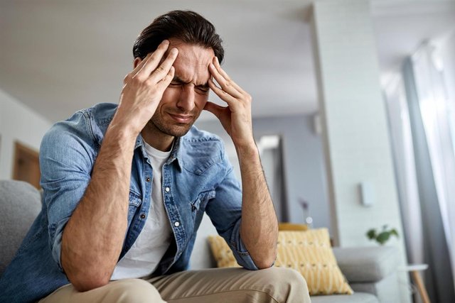 low-angle-view-distraught-man-holding-his-head-pain-while-sitting-living-room.jpg