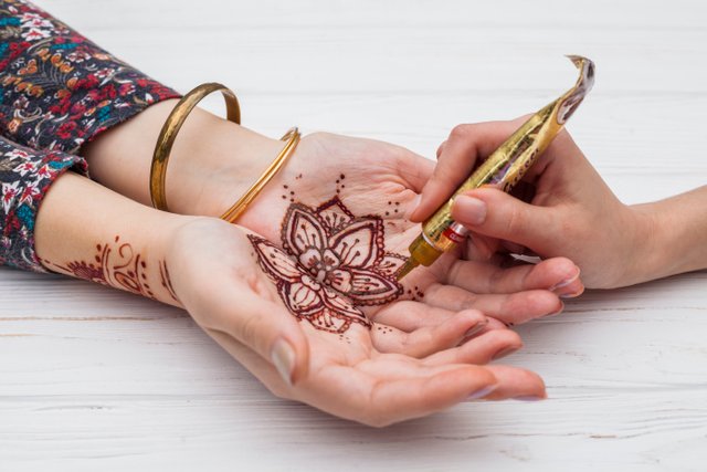 artist-making-mehndi-womans-palms.jpg