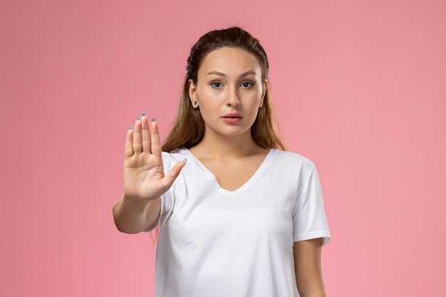 18-13-28-vista-frontal-joven-mujer-atractiva-camiseta-blanca-posando-gesto-prohibicion-sobre-fondo-rosa_140725-26214.jpg