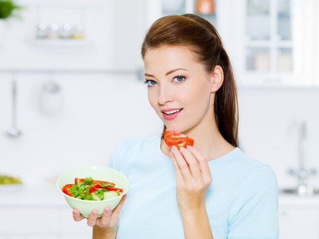 smiling-woman-eat-vegetable-kitchen_186202-3967.jpg