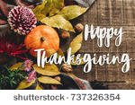 stock-photo-happy-thanksgiving-text-sign-on-autumn-pumpkin-with-leaves-and-walnuts-and-dahlias-on-stylish-scarf-737326354.jpg