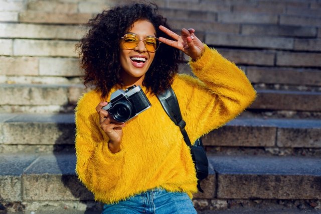 portrait-cheerful-student-girl-with-curly-dark-hair-with-retro-camera-sitting-stairs_273443-2011.jpg