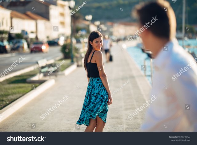 stock-photo-young-attractive-woman-flirting-with-a-man-on-the-street-flirty-smiling-woman-looking-back-on-a-1028640259.jpg