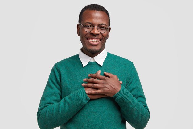handsome-cheerful-black-man-keeps-both-hands-chest-feels-touched-thankful-smiles-broadly-wears-elegant-green-sweater_273609-23587.jpg