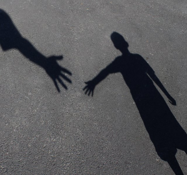 Helping Hand with a shadow of an adult hand offering help or therapy to a child in need as an education concept of charity towards needy kid.jpg