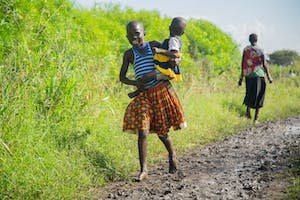 free-photo-of-teenager-carrying-her-baby-sister-running-barefoot-on-a-muddy-path.jpeg