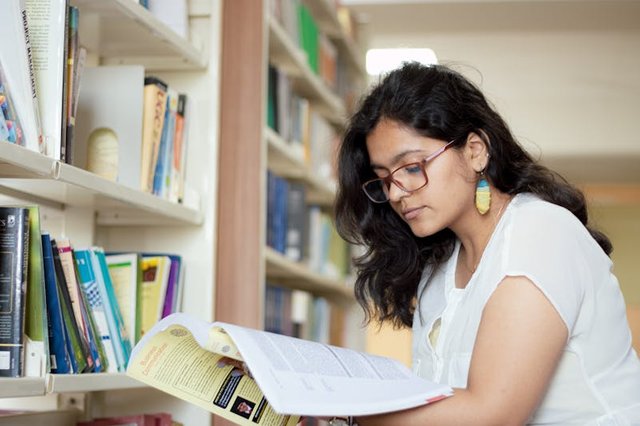 free-photo-of-portrait-of-a-smiling-young-indian-student-reading-a-book-in-a-library.jpeg