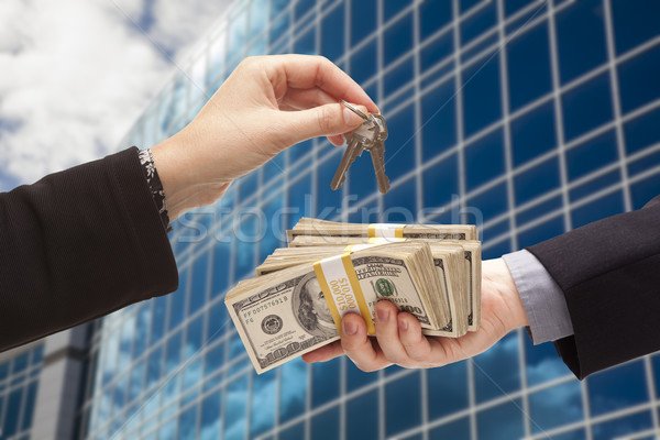 2572288_stock-photo-handing-stack-of-cash-for-key-and-corporate-building.jpg