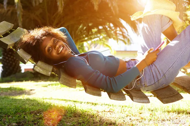 smiling-young-black-woman-listening-music-with-smart-phone_33839-7568.webp