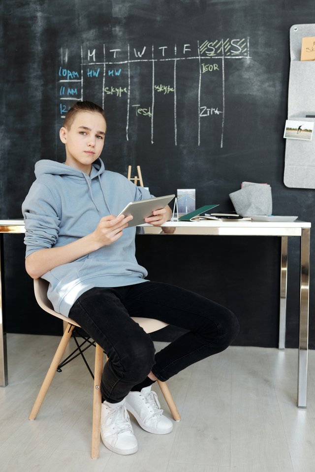 boy-in-gray-hoodie-and-black-pants-while-sitting-on-chair-4144692.jpg