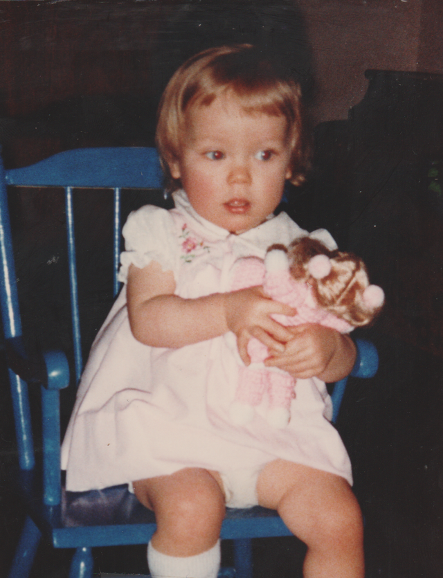 1982 apx - Katie Arnold in a pink dress, Doll, blue rocking chair, maybe at a church.png