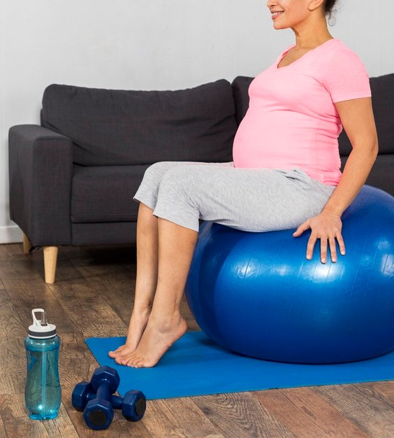 smiley-pregnant-woman-exercising-home-floor-with-ball_23-2148761209.jpg