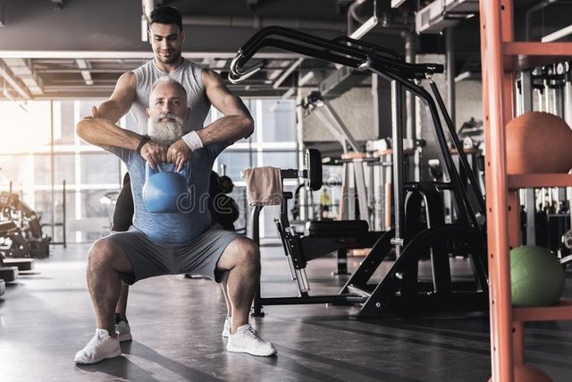 senior-bearded-men-doing-kettlebell-goblet-squats-his-professional-trainer-who-standing-behind-him-correcting-99382432.jpg