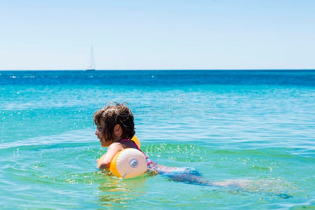 niña-que-se-baña-con-un-flotador-en-la-playa-83000314.jpg