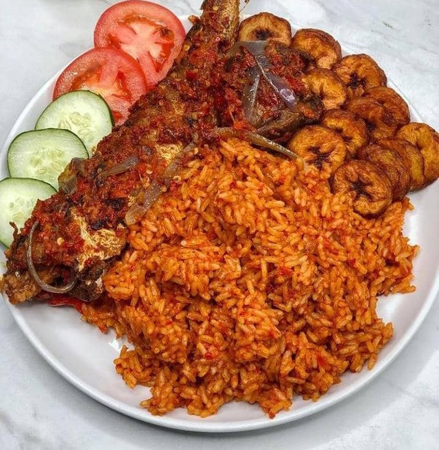 Jollof_rice_with_fried_fish_and_plantains_garnished_with_cucumber_and_tomatoes.jpg