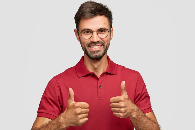 photo-attractive-bearded-young-man-with-cherful-expression-makes-okay-gesture-with-both-hands-likes-something-dressed-red-casual-t-shirt-poses-against-white-wall-gestures-indoor_273609-16239.webp