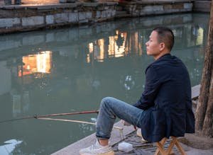 free-photo-of-pensive-man-sitting-by-a-canal-with-a-fishing-rod.jpeg