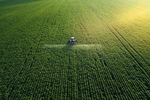 taking-care-of-the-crop-aerial-view-of-a-tractor-fertilizing-a-cultivated-agricultural-field.jpg