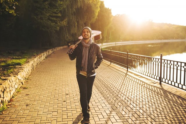 young-man-walks-by-lake-holding-guitar_158595-2033.jpg