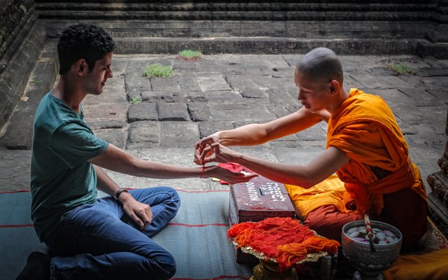 Tying red string bracelet.jpg