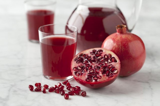 halves-pomegranate-with-seeds-and-pomegranate-juice-on-marbled-surface.jpg