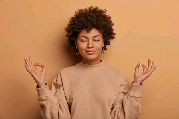 calm-relieved-dark-skinned-woman-takes-deep-breath-keeps-hands-sideways-zen-gessture-reaches-nirvana-practices-yoga-stands-with-closed-eyes-stands-stress-free-against-brown-wall_273609-37601.jpg