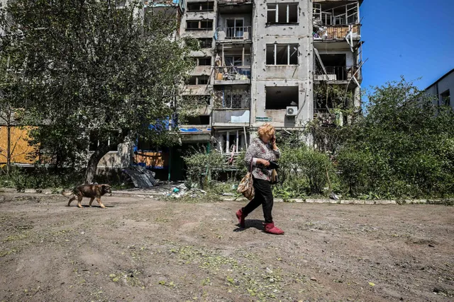 photo-of-a-woman-and-a-dog-walking-past-a-destroyed-building-near-the-lyman-frontline.jpg