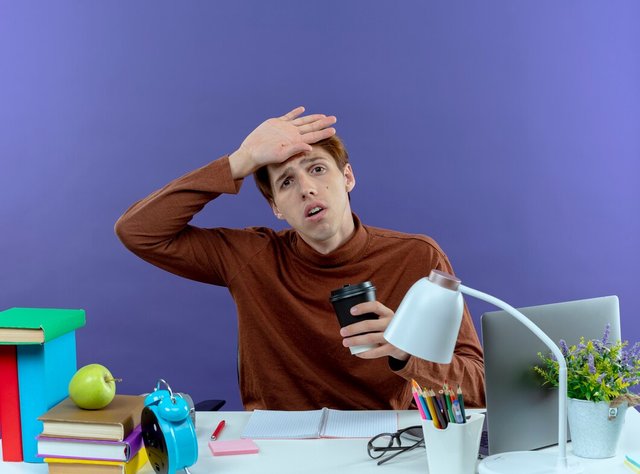 tired-young-studend-boy-sitting-desk-with-school-tools-holding-cup-coffee-putting-hand-forehead-purple_141793-74559.jpg