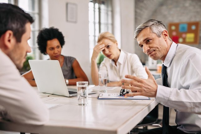 angry-businessman-discussing-with-colleague-during-meeting-office.jpg