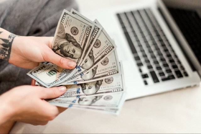 1600951323-close-up-woman-hands-holding-new-dollar-bills-she-earned-working-from-laptop-home-online-97712-81.jpg