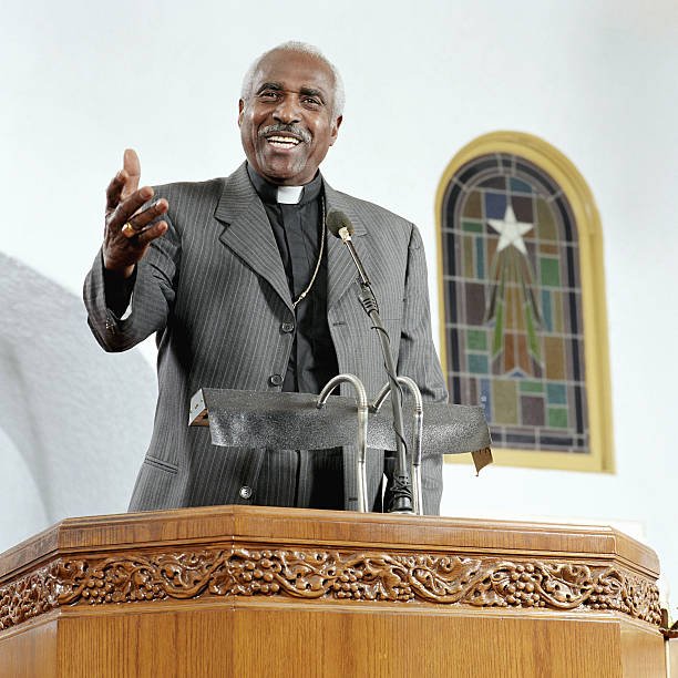 senior-priest-giving-sermon-smiling-low-angle-view-picture-id200267187-001.jpeg