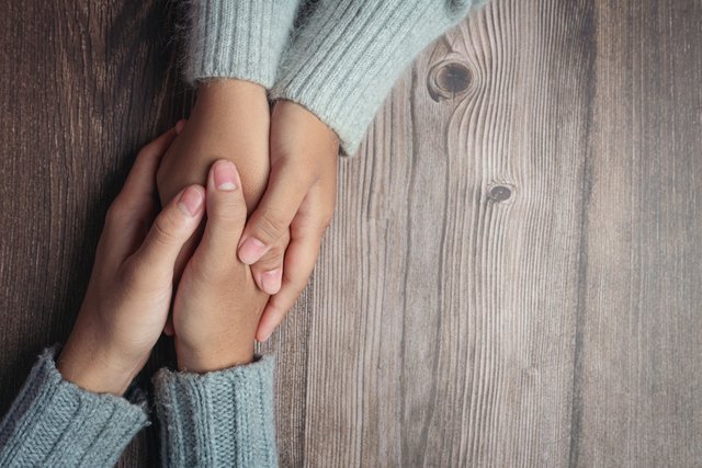 two-people-holding-hands-together-with-love-warmth-wooden-table.jpg
