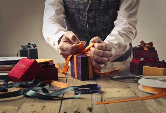 person-tying-ribbon-on-purple-gift-box-1050256.jpg