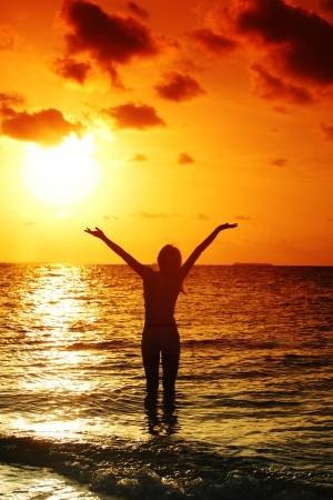 11975139-happy-woman-standing-on-a-sunset-in-ocean-waves.jpg