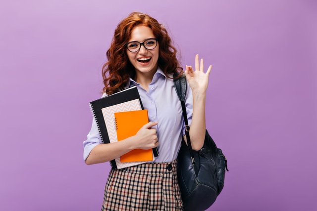 red-haired-lady-eyeglasses-holds-books-shows-ok-sign1.jpg