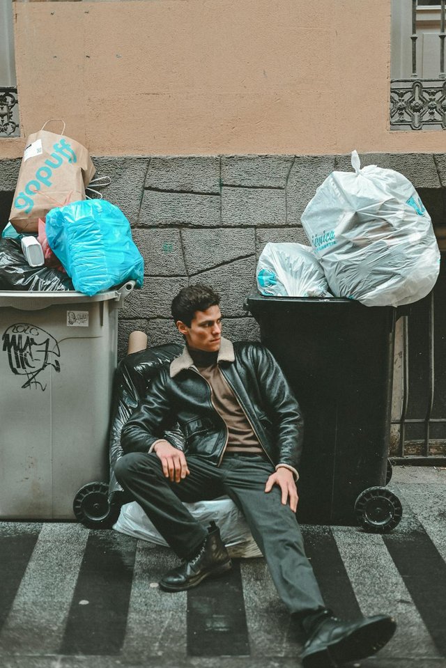 free-photo-of-a-man-sitting-on-the-curb-next-to-a-trash-can.jpeg