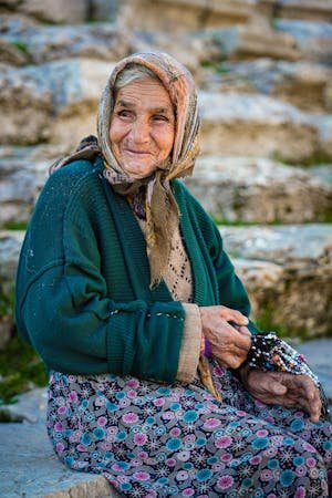 free-photo-of-elderly-woman-in-a-headscarf-sitting-outside-and-smiling.jpeg