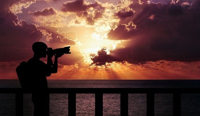 Person using a camera to capture a sunset.