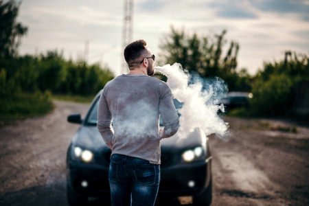 Man Vaping In Front Of Luxury Car