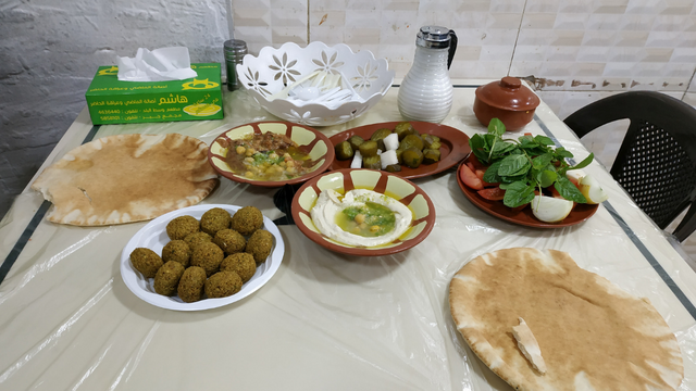 Hummus, Falafel, fresh bread, a plate of Moutabel, fresh veggies and pickles in the famous Hashem restaurant