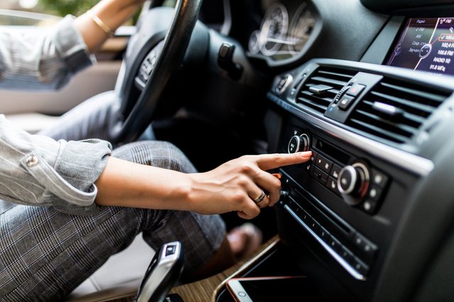 car-dashboard-radio-closeup-woman-sets-up-radio-while-driving-car (1)