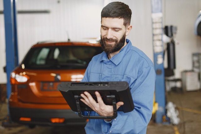 car-mechanic-with-tablet-near-car-work-clothes_1157-46144