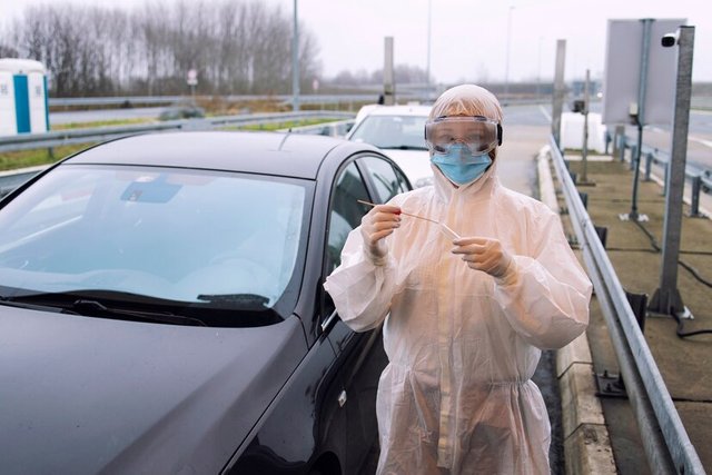 medical-heath-care-worker-protective-white-suit-standing-border-crossing-ready-test-passengers-corona-virus_308072-42