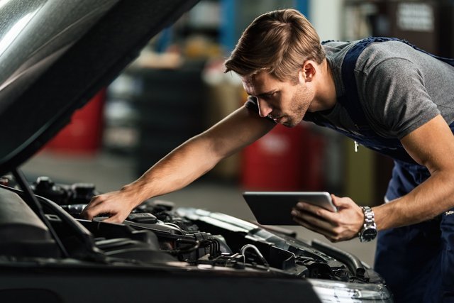 car-mechanic-examining-engine-malfunction-while-using-touchpad-auto-repair-shop-min-Easy-Resize-com.jpg