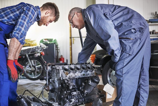 mechanics-repairing-car-workshop-1